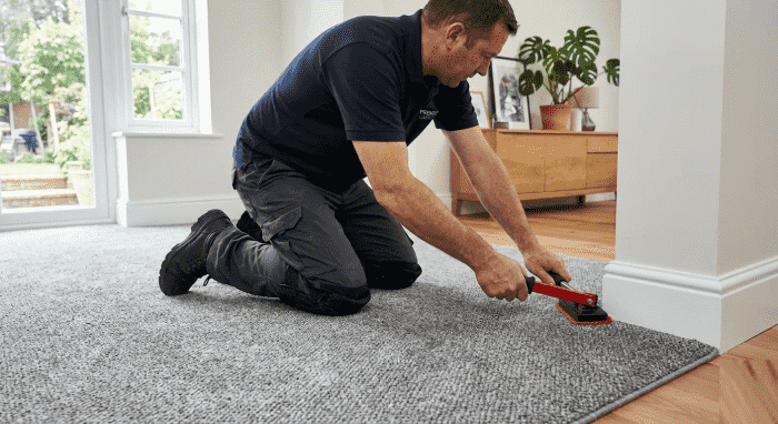 Grey loop-pile carpet being fitted in a living room